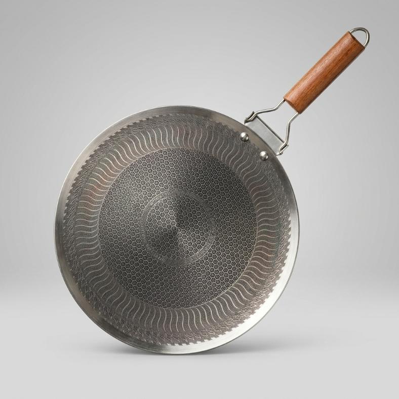 Top-down studio shot of a laser-etched honeycomb stainless steel roti tawa featuring a detailed hexagonal cooking surface and a wooden handle.